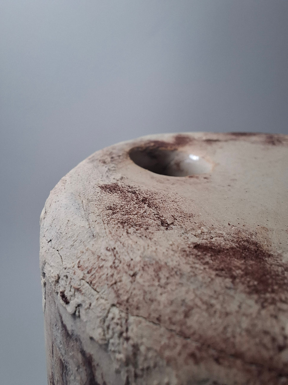 Close-up of the top of Rubble Vase I, showing the irregular hand-cut opening and rust-coloured mineral pigment across the cream stoneware surface.