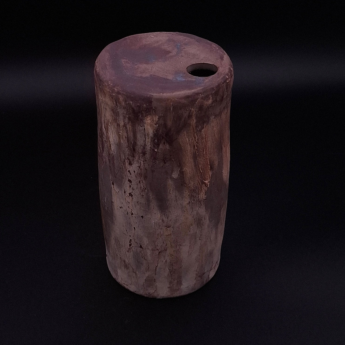 Handmade Rubble Vase III in dark anthracite stoneware, showing its cylindrical form, burnished mineral surface and small opening against a black background.