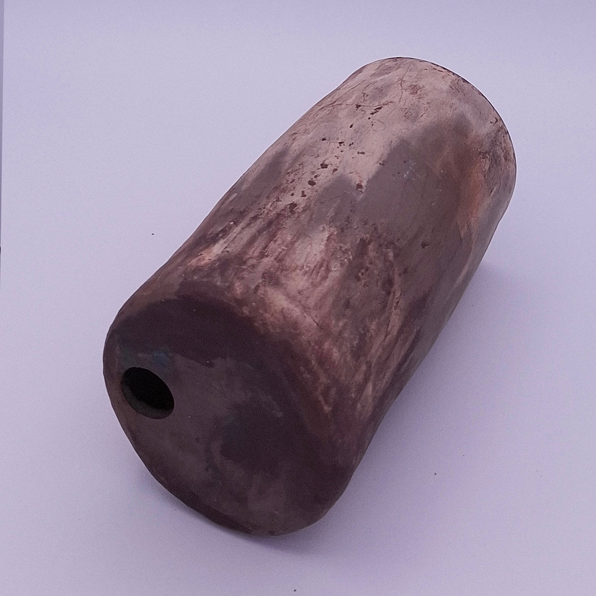 Side view of handmade Rubble Vase III in anthracite stoneware, showing its rounded form, burnished mineral surface and small opening.
