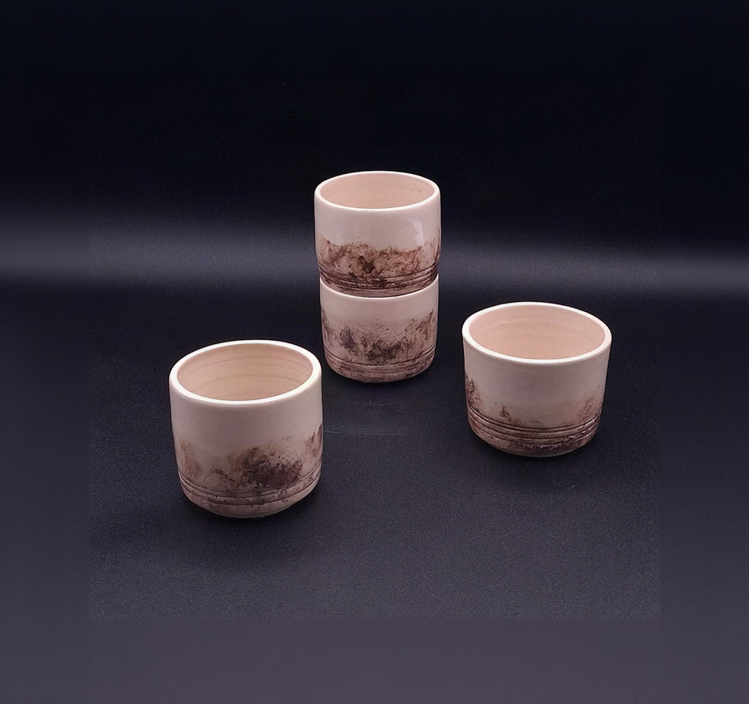 Three handmade 200 ml stoneware Yunomi cups with natural cream surfaces and irregular dark iron oxide patterns, arranged on a dark background.