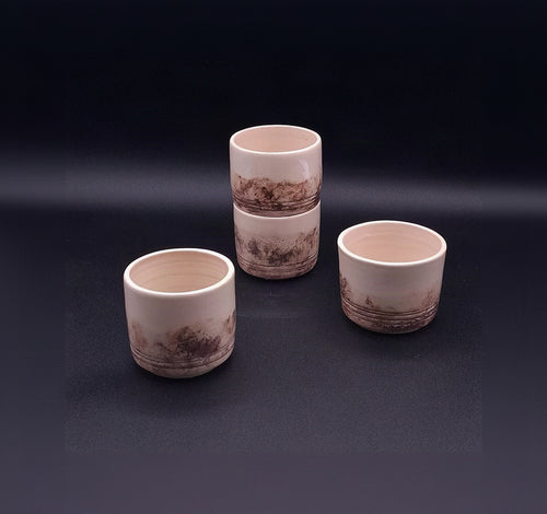 Three handmade 200 ml stoneware Yunomi cups with natural cream surfaces and irregular dark iron oxide patterns, arranged on a dark background.