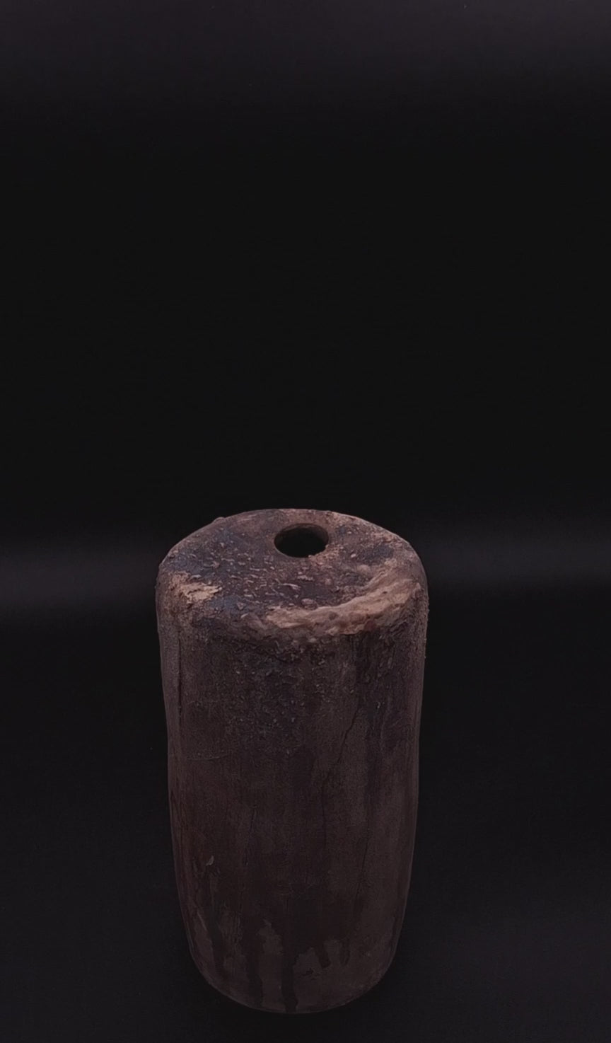 Rubble Vase II, a handmade anthracite stoneware vessel with a dark iron oxide surface and textured top, photographed against a black background.